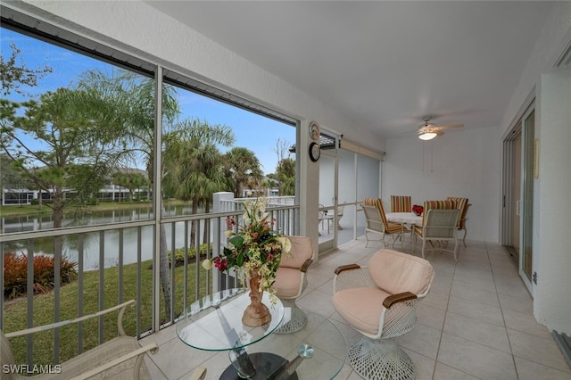 sunroom / solarium featuring ceiling fan and a water view