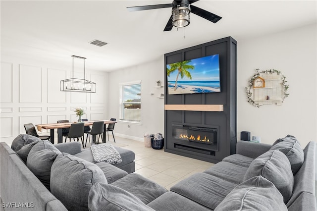 tiled living room with ceiling fan and a fireplace