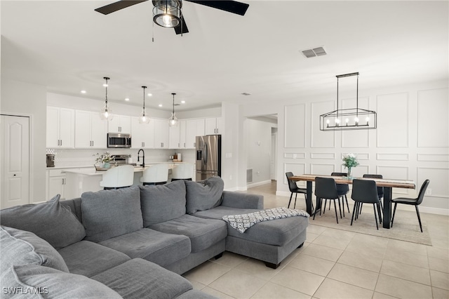 tiled living room with ceiling fan and sink