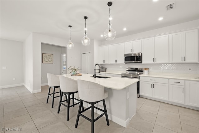 kitchen with sink, appliances with stainless steel finishes, and a kitchen island with sink