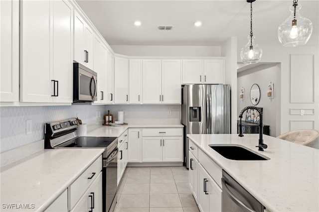 kitchen with light tile patterned floors, white cabinetry, stainless steel appliances, light stone countertops, and sink