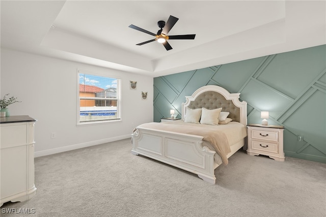 carpeted bedroom with ceiling fan and a raised ceiling