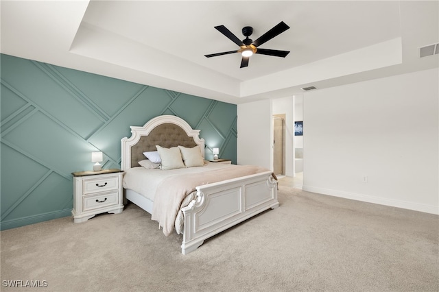 bedroom with ceiling fan, light colored carpet, and a raised ceiling