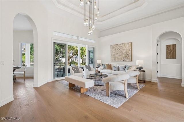 677 5th Ave N, Naples, FL 34102 - living room with arched walkways, wood finished floors, ornamental molding, a tray ceiling, and a towering ceiling