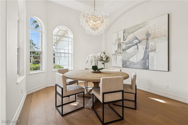 dining space with hardwood / wood-style flooring and an inviting chandelier