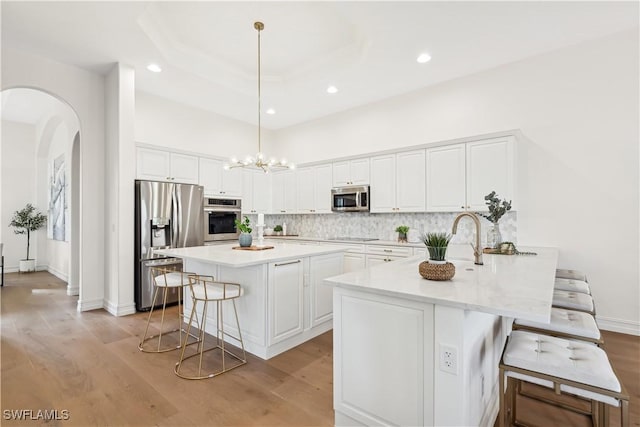 kitchen featuring a kitchen bar, white cabinetry, kitchen peninsula, pendant lighting, and stainless steel appliances