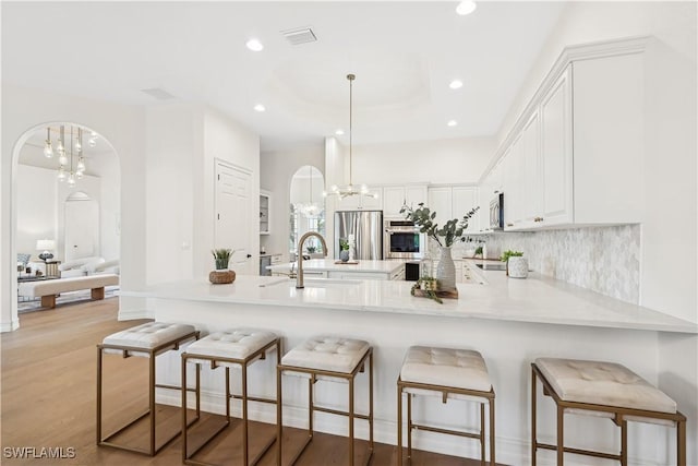 677 5th Ave N, Naples, FL 34102 - kitchen with a chandelier, appliances with stainless steel finishes, a peninsula, light countertops, and recessed lighting