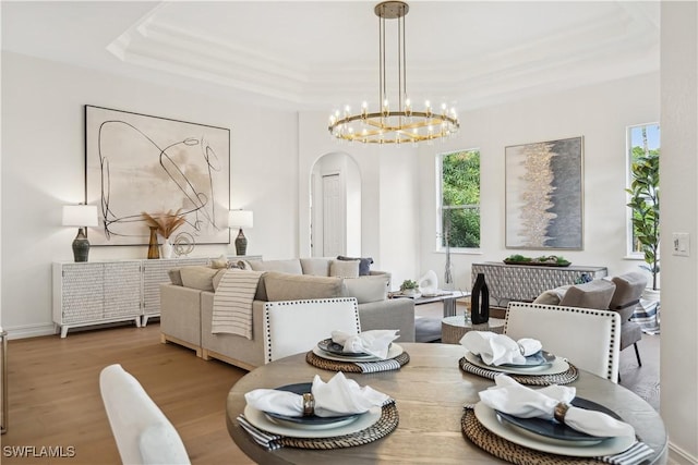 677 5th Ave N, Naples, FL 34102 - dining space featuring arched walkways, a tray ceiling, a chandelier, and wood finished floors