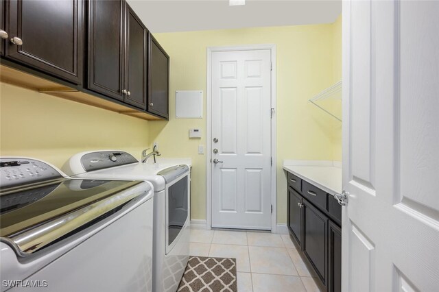 clothes washing area featuring cabinet space, washing machine and dryer, light tile patterned flooring, a sink, and baseboards