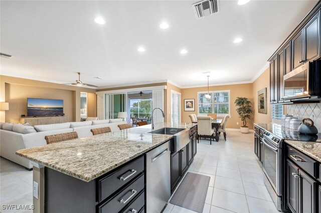 kitchen with a center island with sink, visible vents, appliances with stainless steel finishes, crown molding, and a sink