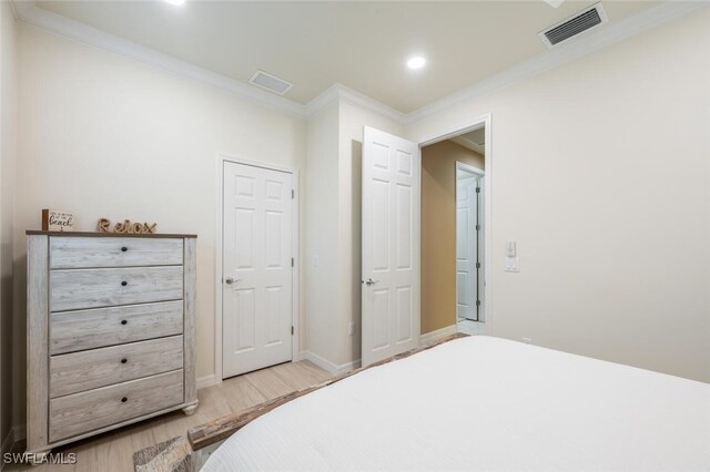 bedroom with ornamental molding, light wood-type flooring, visible vents, and baseboards