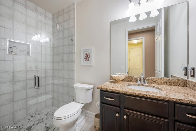 bathroom with vanity, toilet, and a shower with door