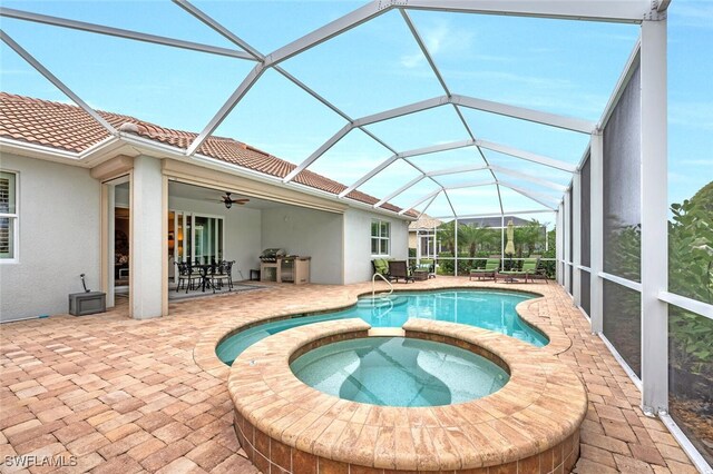 view of swimming pool with ceiling fan, glass enclosure, a pool with connected hot tub, outdoor dining space, and a patio area