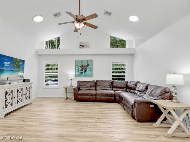 living room featuring ceiling fan, light wood-type flooring, and a towering ceiling