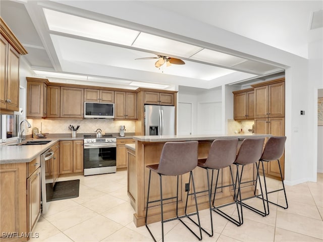 kitchen with a center island, decorative backsplash, light tile patterned flooring, sink, and appliances with stainless steel finishes