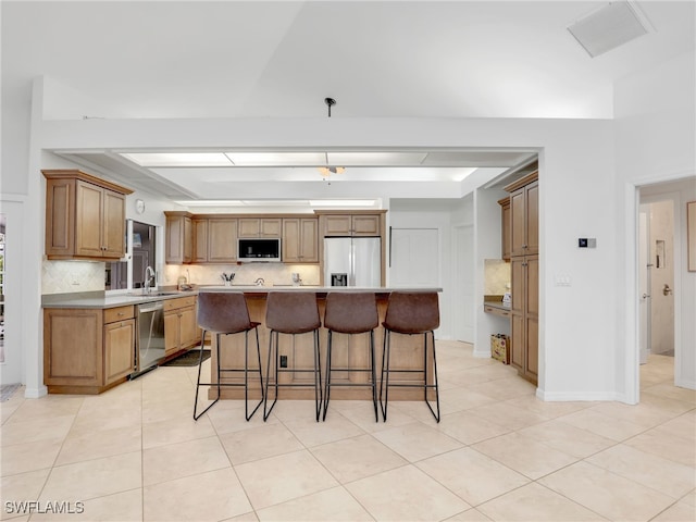 kitchen with appliances with stainless steel finishes, a kitchen island, tasteful backsplash, sink, and a kitchen breakfast bar