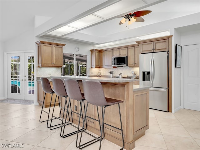 kitchen featuring a kitchen island, stainless steel appliances, french doors, ceiling fan, and light tile patterned floors