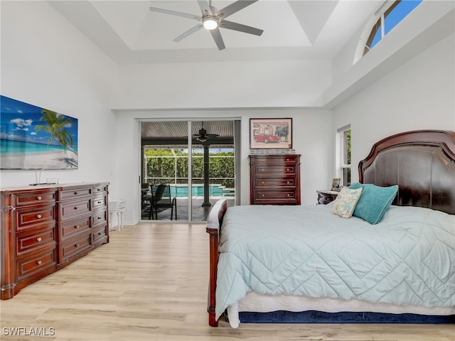 bedroom featuring ceiling fan, access to exterior, a raised ceiling, and light wood-type flooring