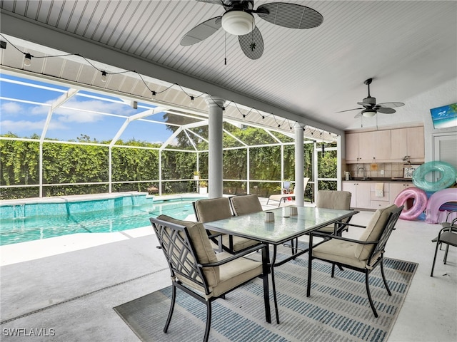 view of swimming pool featuring ceiling fan, a wet bar, a patio, and glass enclosure