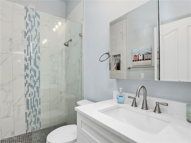 bathroom featuring toilet, tiled shower, and vanity