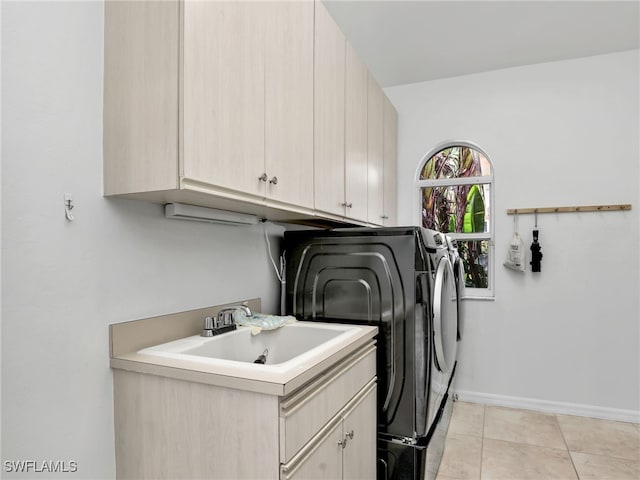 washroom featuring light tile patterned flooring, sink, washing machine and clothes dryer, and cabinets