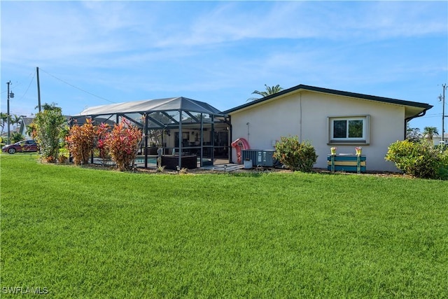 back of house with a lanai and a lawn