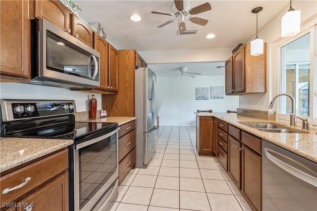 kitchen featuring sink, pendant lighting, ceiling fan, stainless steel appliances, and light stone countertops