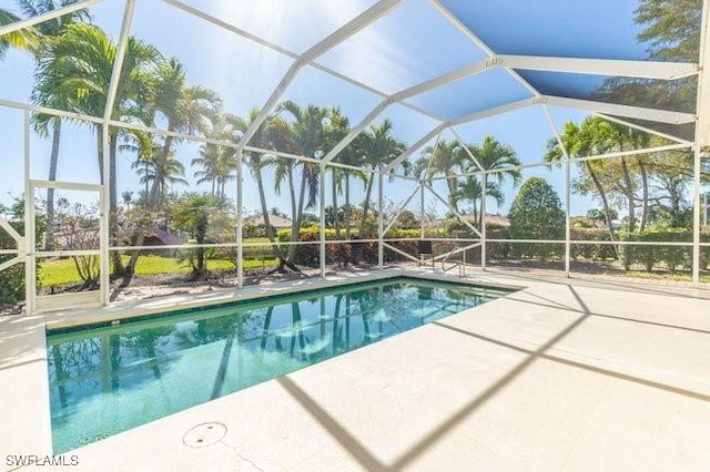 view of pool with glass enclosure and a patio area