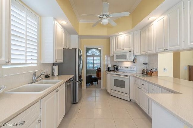 kitchen with sink, white appliances, white cabinetry, ornamental molding, and light tile patterned floors