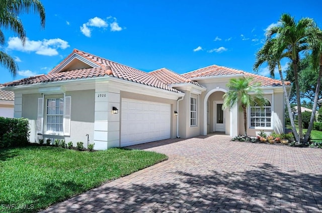 mediterranean / spanish home with a front lawn and a garage