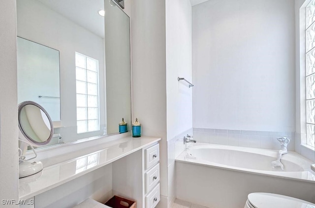 bathroom featuring toilet, a bath, and vanity