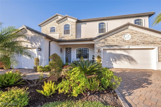 view of front facade featuring an attached garage, stone siding, decorative driveway, and stucco siding