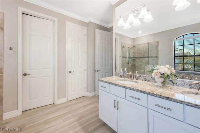 bathroom with wood finished floors, ornamental molding, a stall shower, and a sink