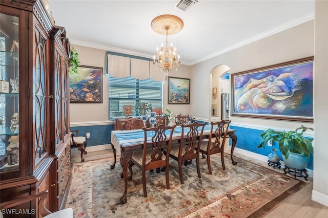 dining room featuring hardwood / wood-style floors, ornamental molding, and an inviting chandelier