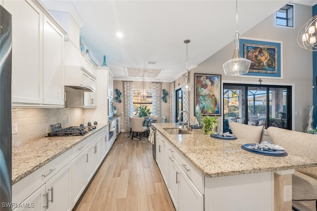 kitchen with sink, pendant lighting, white cabinets, and a kitchen island with sink