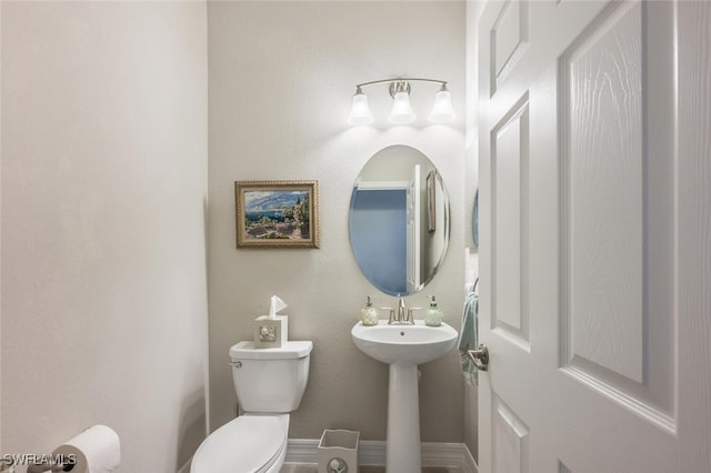 bathroom featuring toilet, baseboards, and a sink