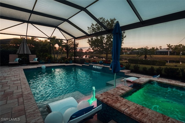 outdoor pool featuring glass enclosure and a patio