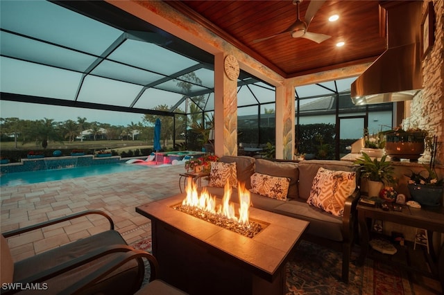 exterior space featuring glass enclosure, an outdoor living space with a fire pit, a hot tub, ceiling fan, and a patio