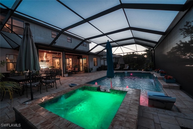 view of swimming pool featuring glass enclosure, a patio area, and a pool with connected hot tub