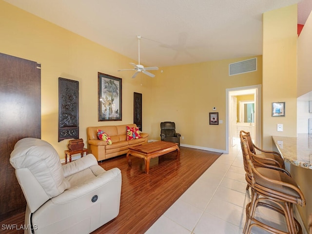 living room with lofted ceiling, ceiling fan, and light tile patterned flooring