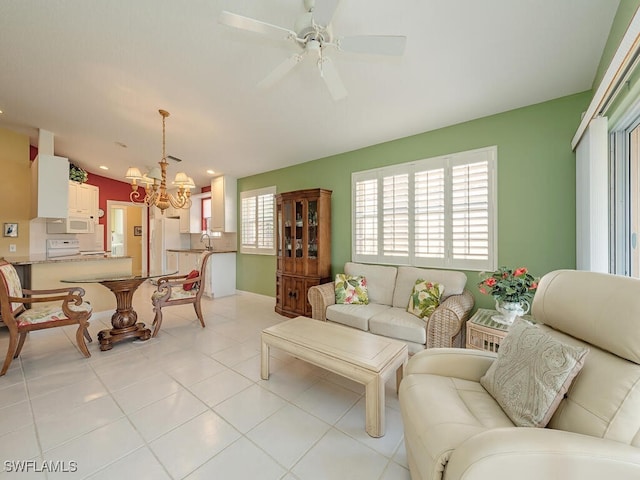 tiled living room featuring ceiling fan with notable chandelier and sink