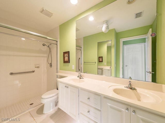 bathroom featuring tile patterned floors, vanity, a tile shower, and toilet