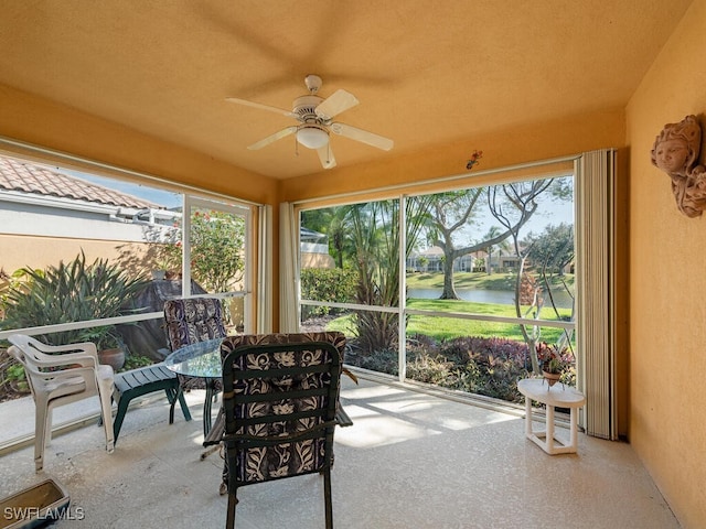 sunroom / solarium with ceiling fan, a wealth of natural light, and a water view