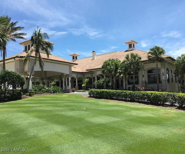 back of property with a tile roof and a lawn