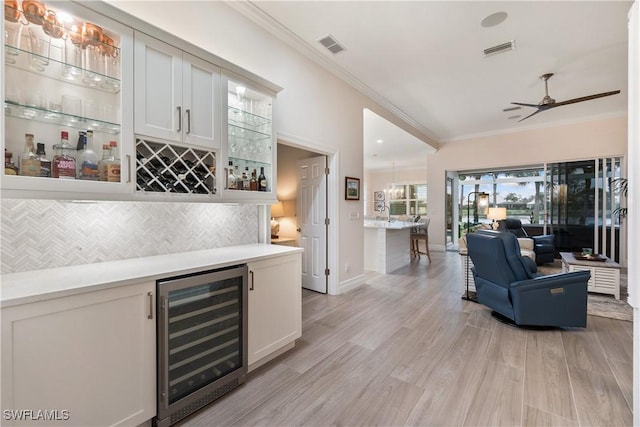 bar with ornamental molding, wine cooler, visible vents, and a dry bar