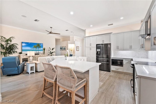 kitchen featuring a breakfast bar area, tasteful backsplash, open floor plan, a sink, and stainless steel fridge with ice dispenser