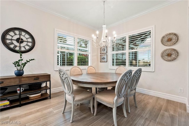 dining space featuring light wood-type flooring, a notable chandelier, crown molding, and baseboards