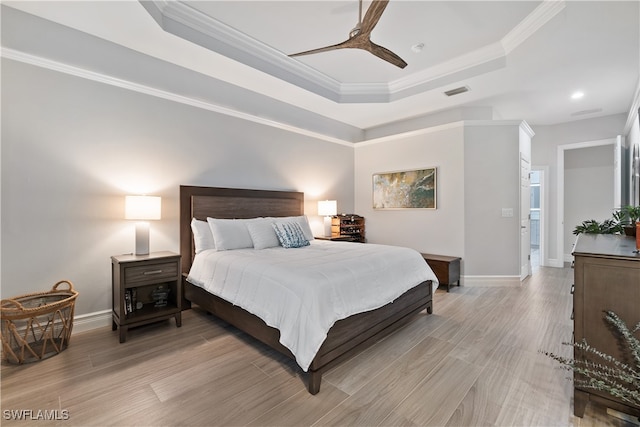 bedroom featuring a tray ceiling, light wood-style flooring, and crown molding