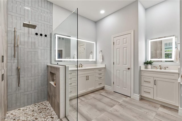 bathroom with two vanities, a sink, wood finished floors, baseboards, and a walk in shower