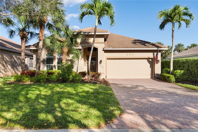 mediterranean / spanish home with a tile roof, an attached garage, decorative driveway, a front lawn, and stucco siding